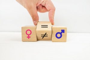 Una mano sta cambiando in "uguale" il simbolo matematico di "diverso" tra i simboli identificativi dei generi femminile e maschile.